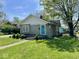 Charming single-story home featuring a manicured lawn, stone facade, and a vibrant blue front door, all under a sunny sky at 5841 E Julian Ave, Indianapolis, IN 46219