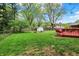 Spacious backyard with green grass, mature trees, a storage shed, and a red deck at 7804 Wawasee Dr, Indianapolis, IN 46250