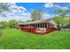 Expansive backyard featuring lush green grass, mature trees, and a red deck attached to the house at 7804 Wawasee Dr, Indianapolis, IN 46250