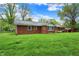 Rear exterior view of a brick home with an expansive green lawn and mature trees at 7804 Wawasee Dr, Indianapolis, IN 46250