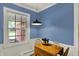 Charming dining area with blue walls, wainscoting, natural light from the large window, and a small wooden table at 7804 Wawasee Dr, Indianapolis, IN 46250