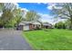 Front exterior showcasing a home with a well-maintained lawn and a long driveway leading to a garage at 7804 Wawasee Dr, Indianapolis, IN 46250