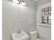 Small powder room featuring a toilet, sink, overhead lighting, and a window for plenty of natural light at 7804 Wawasee Dr, Indianapolis, IN 46250