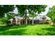 Sprawling backyard with a lush lawn, patio with an outdoor fireplace, and Tudor home at 8103 N Pennsylvania St, Indianapolis, IN 46240