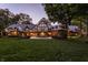 Tudor-style home with outdoor seating area, lush green lawn, and warm exterior lighting at 8103 N Pennsylvania St, Indianapolis, IN 46240