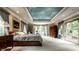 A bright main bedroom featuring a decorative tray ceiling, two windows, and access to a private terrace at 8103 N Pennsylvania St, Indianapolis, IN 46240