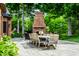 Stone patio with a dining table, an outdoor fireplace, and lush greenery at 8103 N Pennsylvania St, Indianapolis, IN 46240