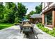 Covered patio with an outdoor dining area, mature trees, and lush landscaping at 8103 N Pennsylvania St, Indianapolis, IN 46240