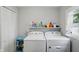 Laundry room with white washer and dryer, shelf with cleaning supplies, and a window at 842 Miller Ave, Shelbyville, IN 46176