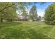 Expansive backyard with lush green lawn and mature trees, including a back view of the house and garage at 8814 E 146Th St, Noblesville, IN 46060