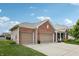A three car attached garage on a brick home, with a long driveway and lawn at 8855 Banner Dr, Brownsburg, IN 46112
