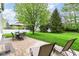 A beautiful backyard with a stone patio, an outdoor dining set, lounge chairs, and a large shade tree at 10524 Hawks Ridge Ct, Fishers, IN 46037