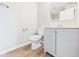 Bright bathroom features a toilet, vanity with gray cabinets, new mirror, and wood-look vinyl flooring at 108 W Cross St, Anderson, IN 46012