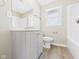 Bright bathroom features a toilet, vanity with gray cabinets, new mirror, and wood-look vinyl flooring at 108 W Cross St, Anderson, IN 46012