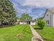 Landscaped front yard leading to a charming home featuring mature trees and a well-manicured lawn at 108 W Cross St, Anderson, IN 46012