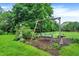 Wood swing set in backyard, surrounded by mature trees and landscaping at 1095 Williamsburg Ln, Zionsville, IN 46077