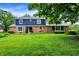 Classic two-story home with brick and blue siding, complemented by a lush green lawn and mature trees at 1095 Williamsburg Ln, Zionsville, IN 46077