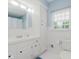 Clean bathroom featuring a white vanity, neutral blue walls, a window, and a toilet with white floor tiles at 1101 High Ct, Carmel, IN 46033
