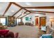 Inviting living room with vaulted ceilings, wooden beams, brick fireplace and a large tv at 12142 N Paddock Rd, Camby, IN 46113