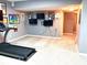 Finished basement with exercise equipment, mounted TVs, neutral carpet, and access to hallway at 13766 Heatherfield Dr, Fishers, IN 46038