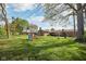 Spacious backyard with mature trees, a brick home, and a play set at 1416 Wellington Ave, Indianapolis, IN 46219