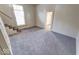 Carpeted living room featuring a window, staircase, and a doorway leading to another room at 1425 S Belmont Ave, Indianapolis, IN 46221