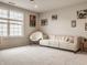 Bright living room with a large window, plush carpeting, and a comfortable leather sofa at 14878 Anees Ln, Fishers, IN 46040