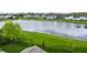 A serene pond view with a fountain, lush greenery, and a glimpse of rooftops from behind a fence at 14878 Anees Ln, Fishers, IN 46040