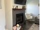 Living room fireplace with gray tile, dark wood mantle, and decoratively displayed above in well-lit living space at 1502 Austin Dr, Lebanon, IN 46052