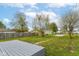 Fenced backyard with grass, shed, and partially visible deck, under a bright cloudy sky at 1523 S K St, Elwood, IN 46036