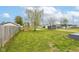 Large grassy backyard featuring mature trees, storage sheds, and a wooden fence at 1523 S K St, Elwood, IN 46036