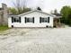 Charming single-story home with white siding, black shutters and a gravel driveway at 223 E 53Rd St, Anderson, IN 46013