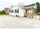 Charming single-story home with white siding, black shutters and a gravel driveway at 223 E 53Rd St, Anderson, IN 46013