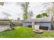 Fenced backyard featuring a lush lawn, fire pit, and detached garage with storage shed at 328 N Layman Ave, Indianapolis, IN 46219