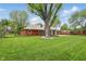 Lush backyard featuring a brick home with a deck, complemented by mature trees and greenery at 4044 Roamin Dr, Greenwood, IN 46142