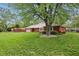 A brick home with green lawn is shaded by a large tree in a well-landscaped suburban setting at 4044 Roamin Dr, Greenwood, IN 46142