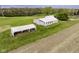 Aerial view showcasing various outbuildings on a vast green lawn, including greenhouses and storage structures at 5707 S Burlington Dr, Muncie, IN 47302