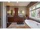 Bathroom with double sinks, wood cabinets, stone accent wall, and stand alone tub at 5925 Silas Moffitt Way, Carmel, IN 46033