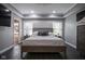 Comfortable main bedroom with dark floors, tray ceiling, and neutral colored walls, including attached bathroom at 5925 Silas Moffitt Way, Carmel, IN 46033
