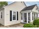 Close-up of the house's front entrance, showcasing a sunroom, black shutters, and manicured landscaping at 6167 Ralston Ave, Indianapolis, IN 46220