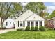 Charming home featuring bright siding, black shutters, a brick chimney, mature landscaping, and a well-manicured lawn at 6167 Ralston Ave, Indianapolis, IN 46220