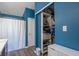 This bathroom features blue accent walls, a shower-tub with curtain and closet with shelves at 623 White Ash Trl, Mooresville, IN 46158