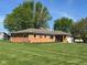 A well-maintained brick home with a tidy lawn, dark mulch beds, and mature trees at 630 Johnson Rd, Mooresville, IN 46158