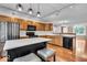 Kitchen features wooden cabinets, black appliances, island with seating, and hardwood floors at 65 Palomino Ct, Zionsville, IN 46077