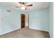 Simple light blue bedroom with carpet, window, ceiling fan, and wooden door at 676 La Placita St, Greenwood, IN 46143