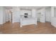 Well-lit kitchen features an island with a sink, white cabinets, and wood flooring at 6871 Seabiscuit Rd, Whitestown, IN 46075