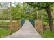 A small wooden bridge with green railings crosses a serene creek surrounded by lush trees at 7126 Nile Ridge Ct, Indianapolis, IN 46236