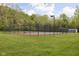 Outdoor tennis court features a tall black fence, and is surrounded by green grass and lush trees at 7126 Nile Ridge Ct, Indianapolis, IN 46236