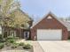 Traditional two-story brick home featuring a two-car garage and professionally landscaped front yard at 7203 Sycamore Run Dr, Indianapolis, IN 46237