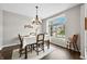 Dining room with modern chandelier, wood table and chairs, and large window seat at 7319 Hartington Pl, Indianapolis, IN 46259